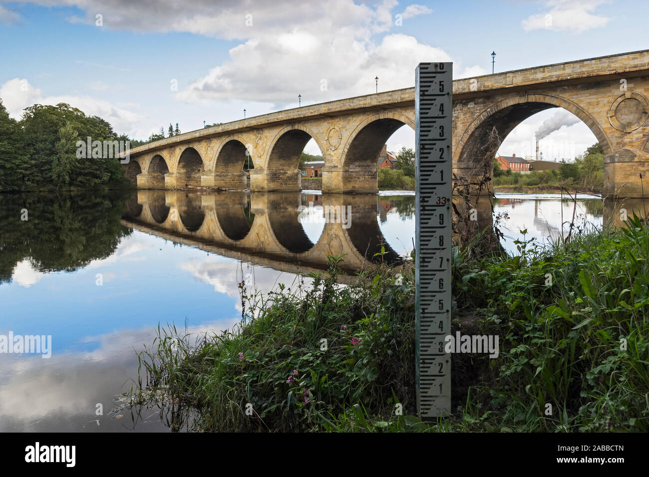 Water/flood level marker on the river Tyne at Hexham with Hexham road bridge spanning the river in Northumberland, UK. Stock Photo