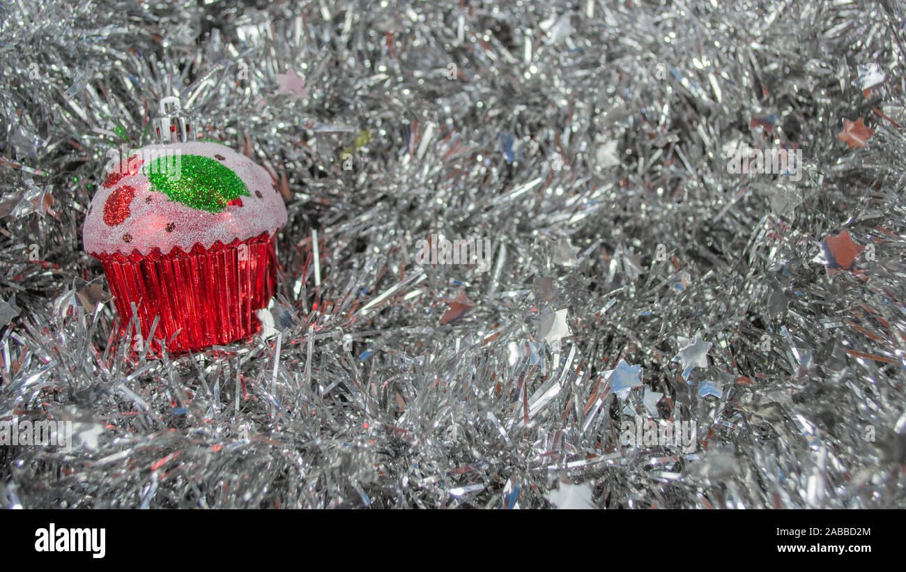 Muffin ornament on silver tinsel background, Christmas decoration with copy space Stock Photo