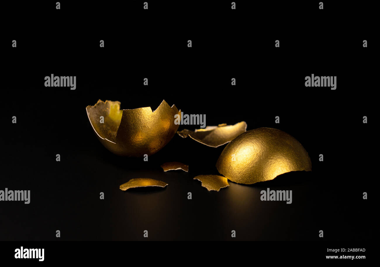 broken Golden egg, Golden shell lying on a black background Stock Photo