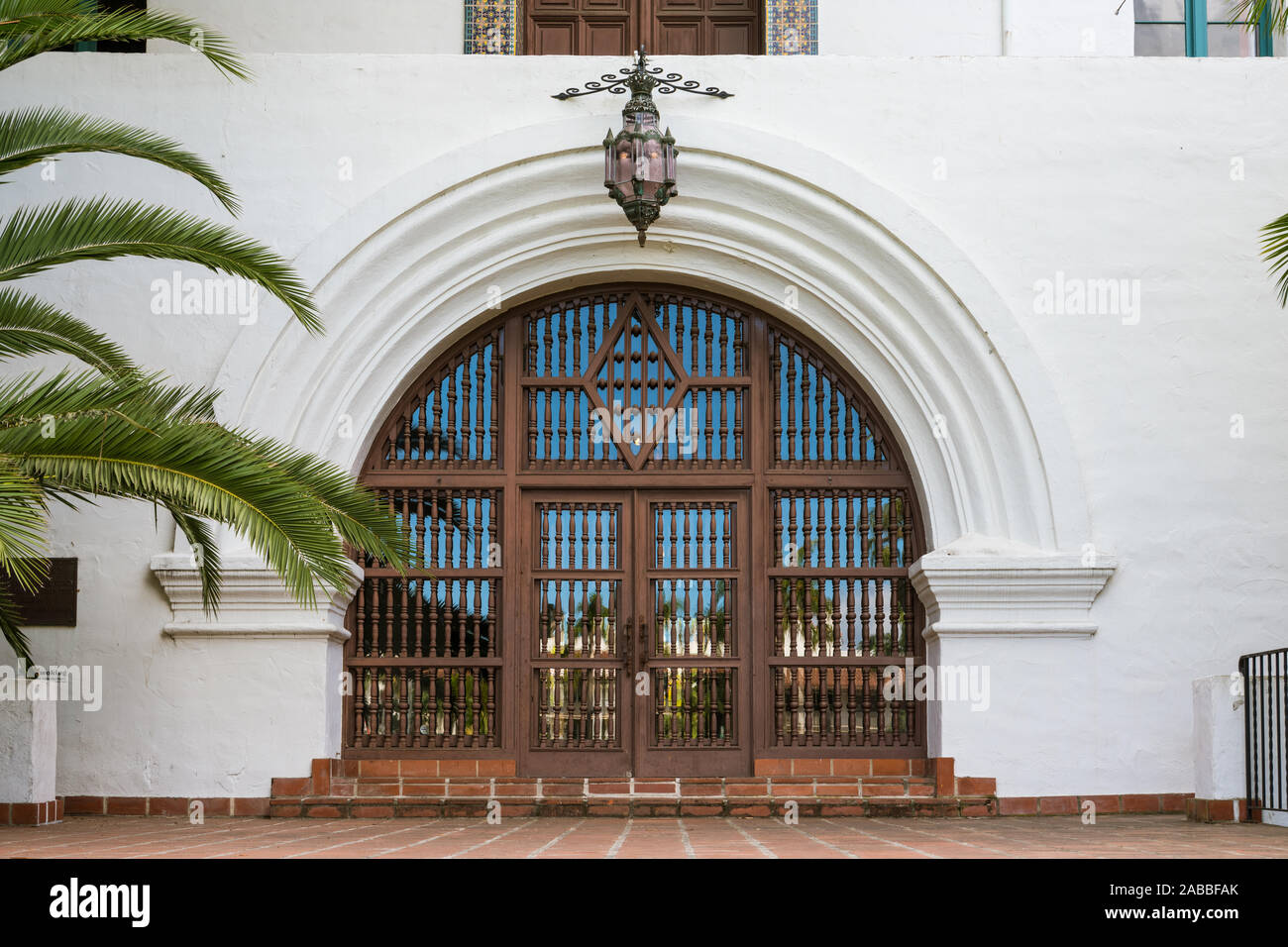 Large ornate wood door in an arched entrance to an historic white Spanish style building in Santa Barbara, California, USA Stock Photo