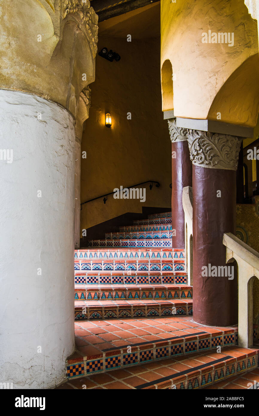 An exterior stairway in  an old Spanish architectural style with beautiful tiles with complex patterns curves through columns in an historic building Stock Photo