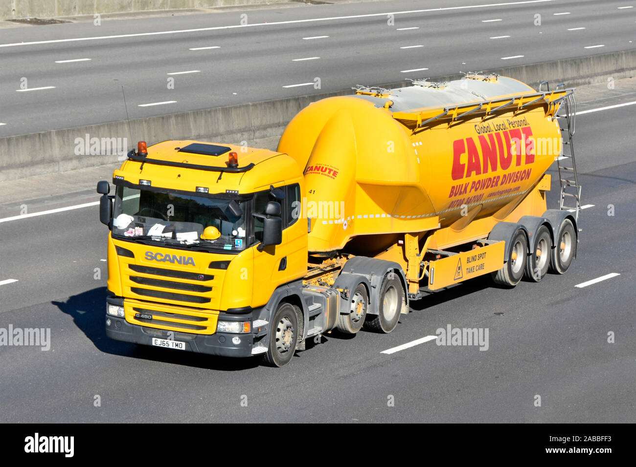 Yellow Canute transport bulk powder supply chain business group tanker trailer & Scania hgv lorry truck with raised axle driving along UK motorway Stock Photo