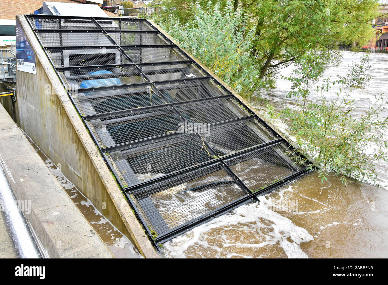 Part of archimedean screw behind security cage being driven by River Wear fast water flow in hydro electricity power generator installation Durham UK Stock Photo