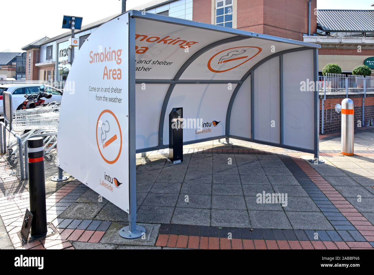 Intu Properties provide smokers a smoking area cubicle shelter at entrance to shopping mall Thurrock Lakeside indoor shopping centre Essex England UK Stock Photo