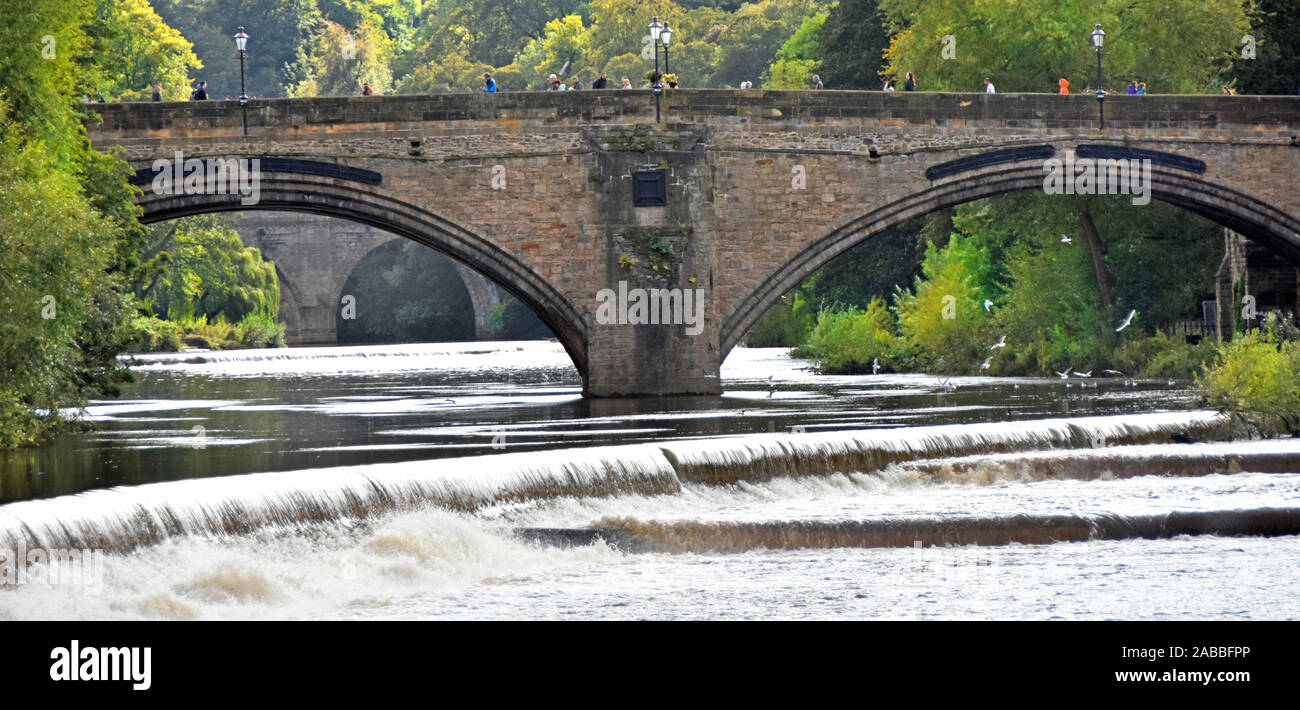 River Wear high potential flooding after heavy rain summer people walking on historical arched Framwellgate Bridge in wet weather in Durham England UK Stock Photo