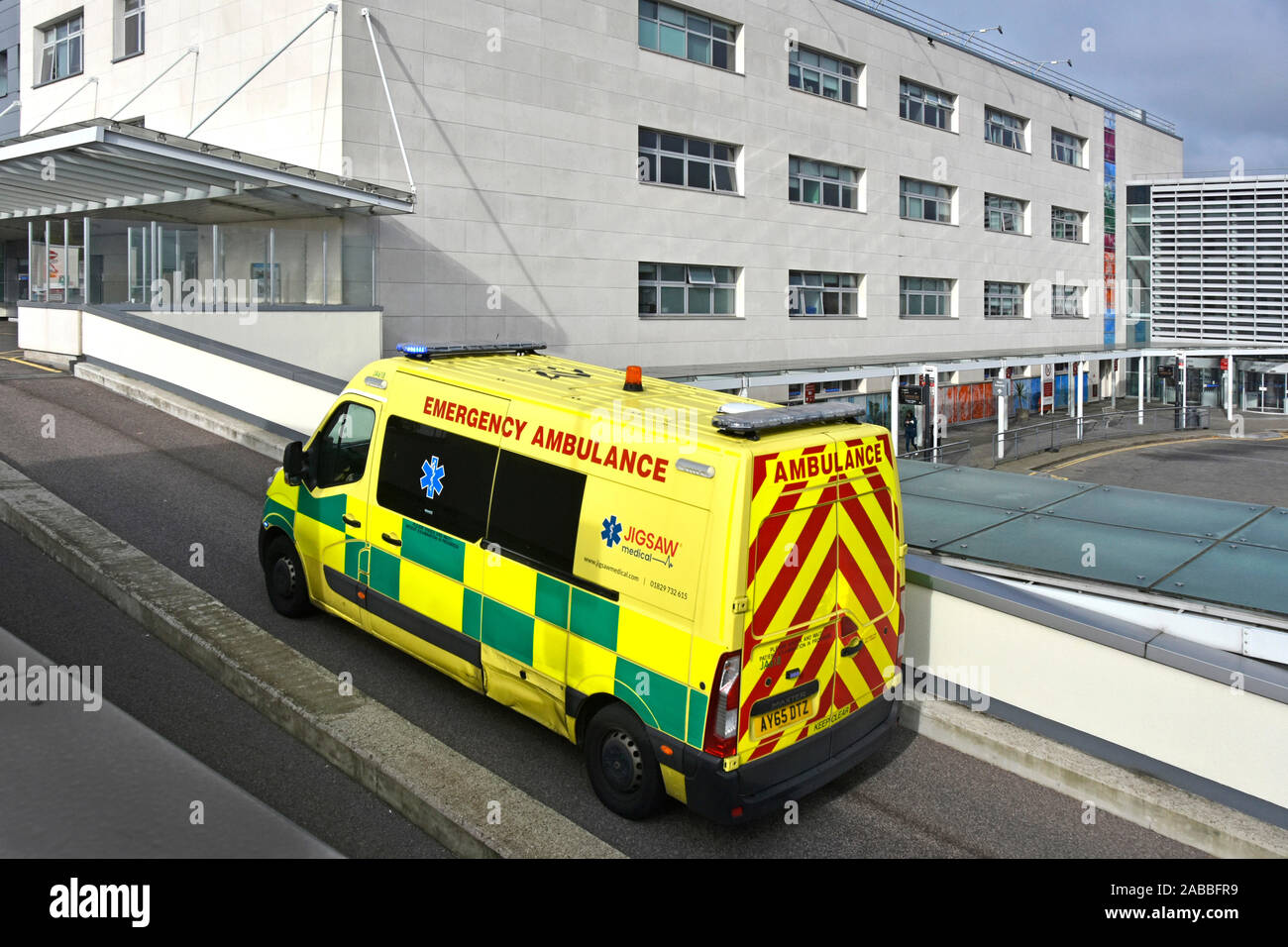 Broomfield NHS Hospital private emergency ambulance a business operated by Jigsaw Medical blue lights on drives up ramp to A&E department in Essex UK Stock Photo