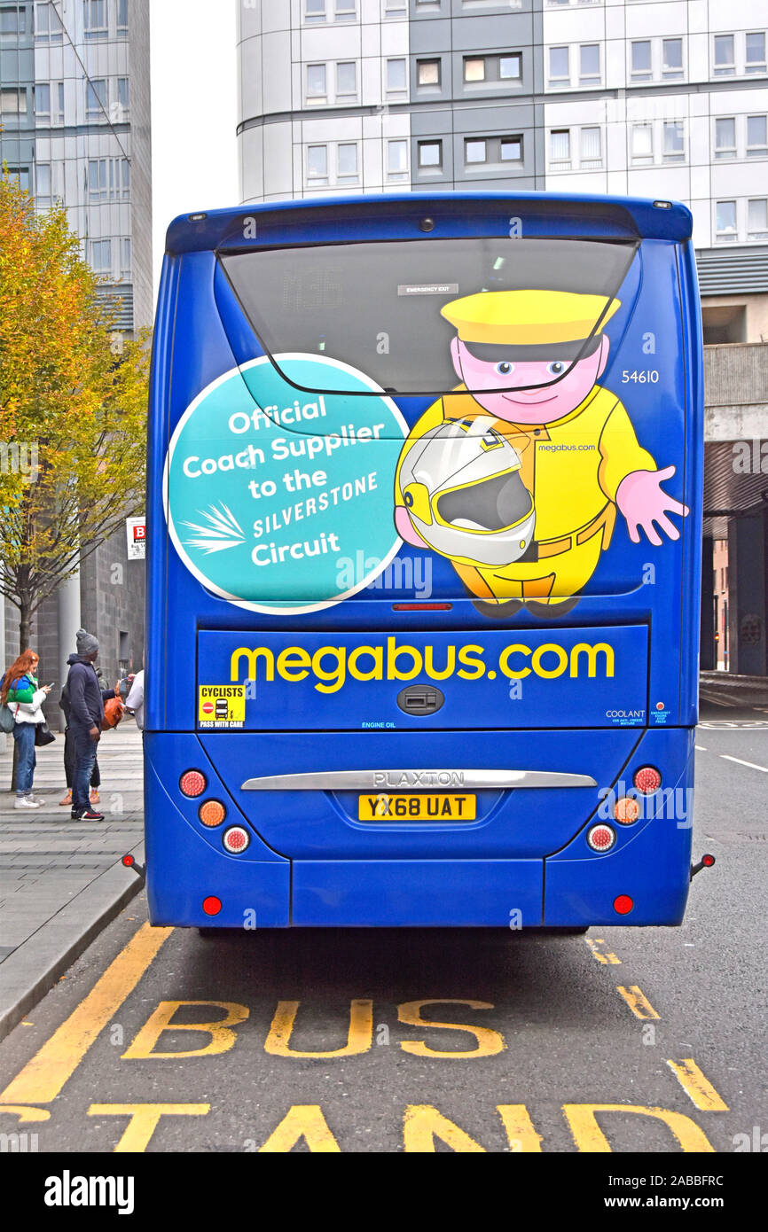 Back view of Megabus.com low cost intercity bus travel people at bus stop in Newcastle advertising for its links with Silverstone circuit England UK Stock Photo