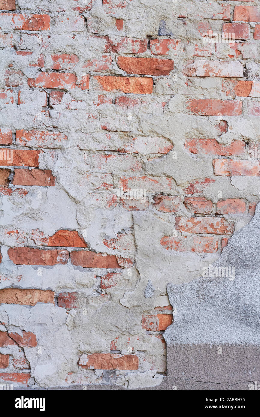 Old weathered red brick wall fragment, crumbling plaster Stock Photo