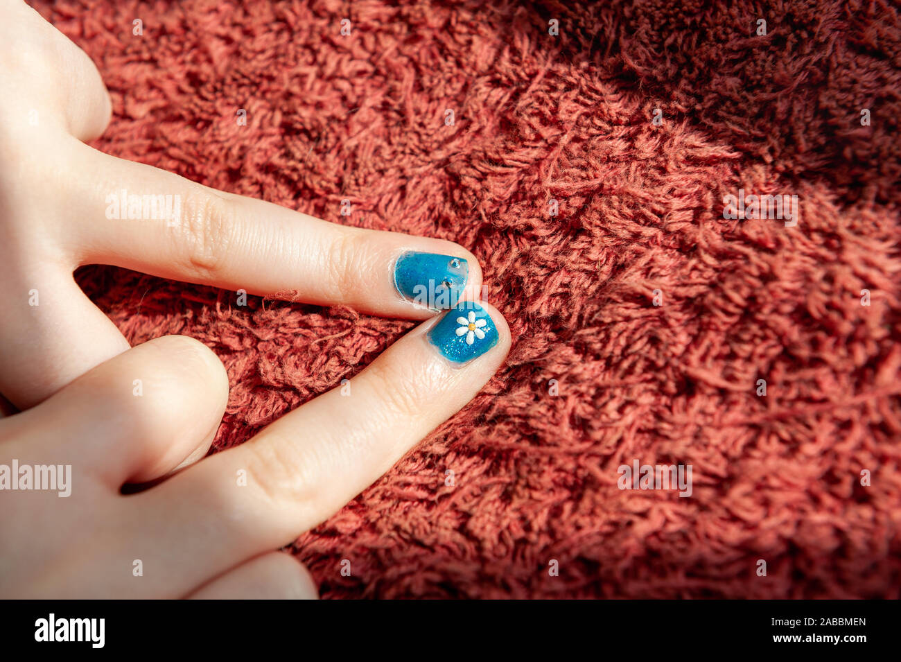 Two blue painted fingernails with flower and eye details Stock Photo