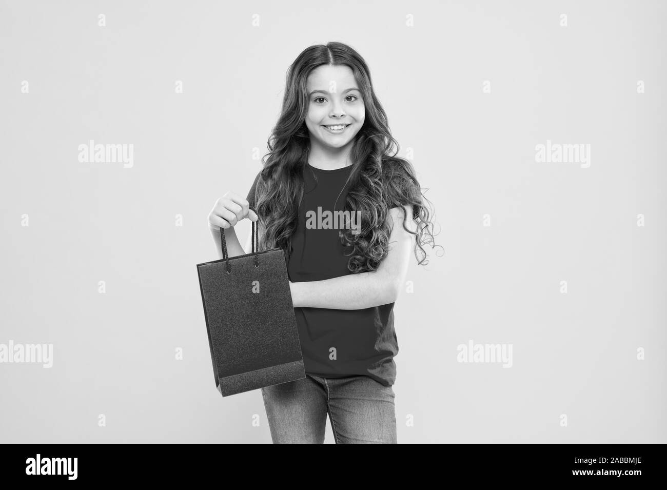 delivery service. child on yellow background. shopping. child with shopping bag. happy girl with long curly hair. little beauty shopaholic. Holiday present. little girl shopping online. happy shopper. Stock Photo