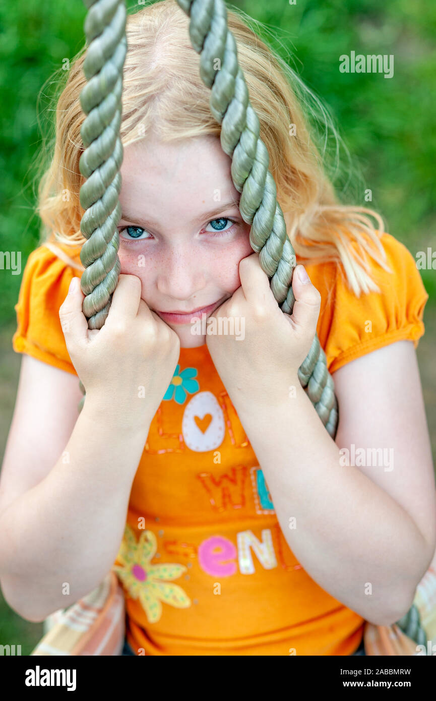 Close up shot of pretty blonde girl's face while clinging to a rope