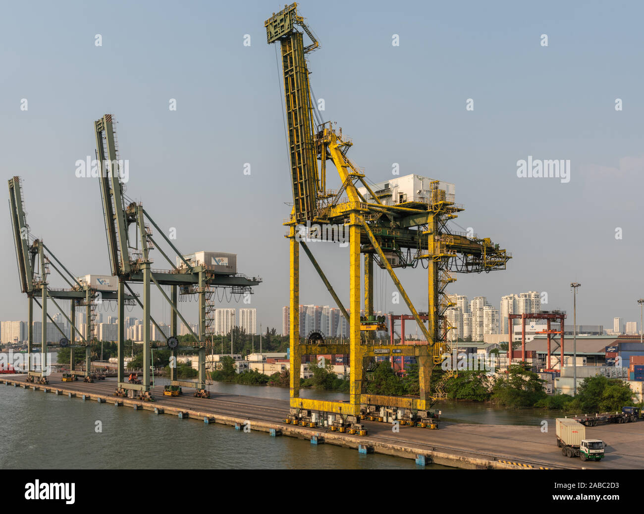Ho Chi Minh City, Vietnam - March 13, 2019: Vict port on Song Sai Gon river at sunset. 3 idle cranes at quay, Residential high rise buildings in back. Stock Photo