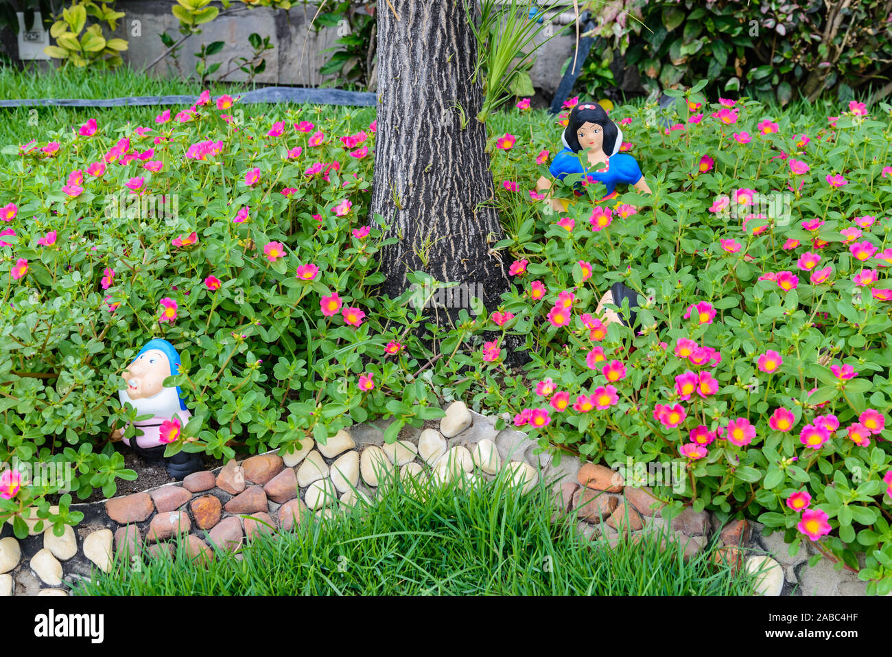 Figurines of Snow White and the Dwarves in a flower garden. Brazil, South America. Stock Photo