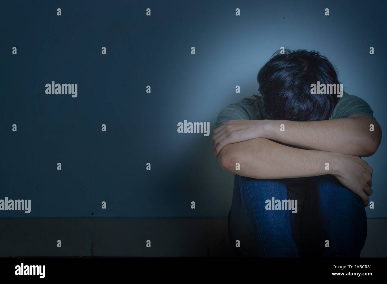 sad man hug his knee and cry sitting alone in a dark room. Depression ...