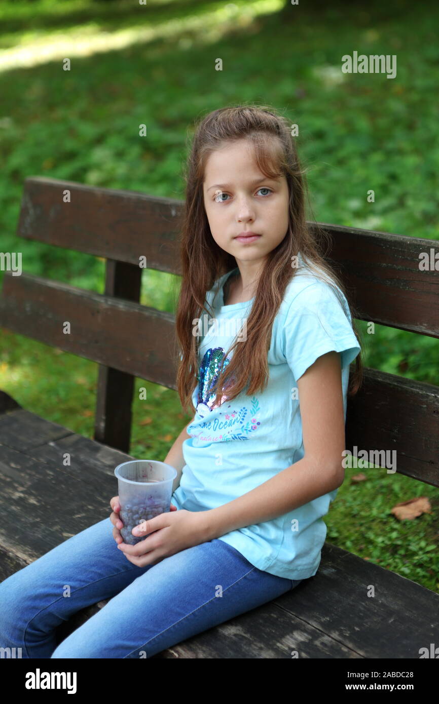 Little girl sits on a bench and eats blueberries Stock Photo - Alamy