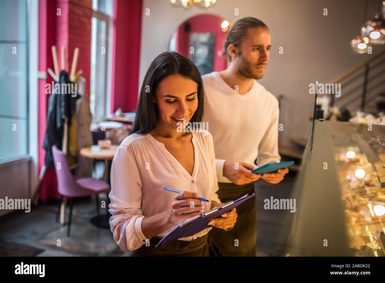 Businesswoman making notes while ordering foods with husband Stock Photo