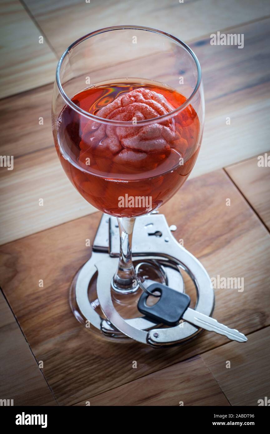 Human brain in red wine glass soaking with car keys and handcuffs for