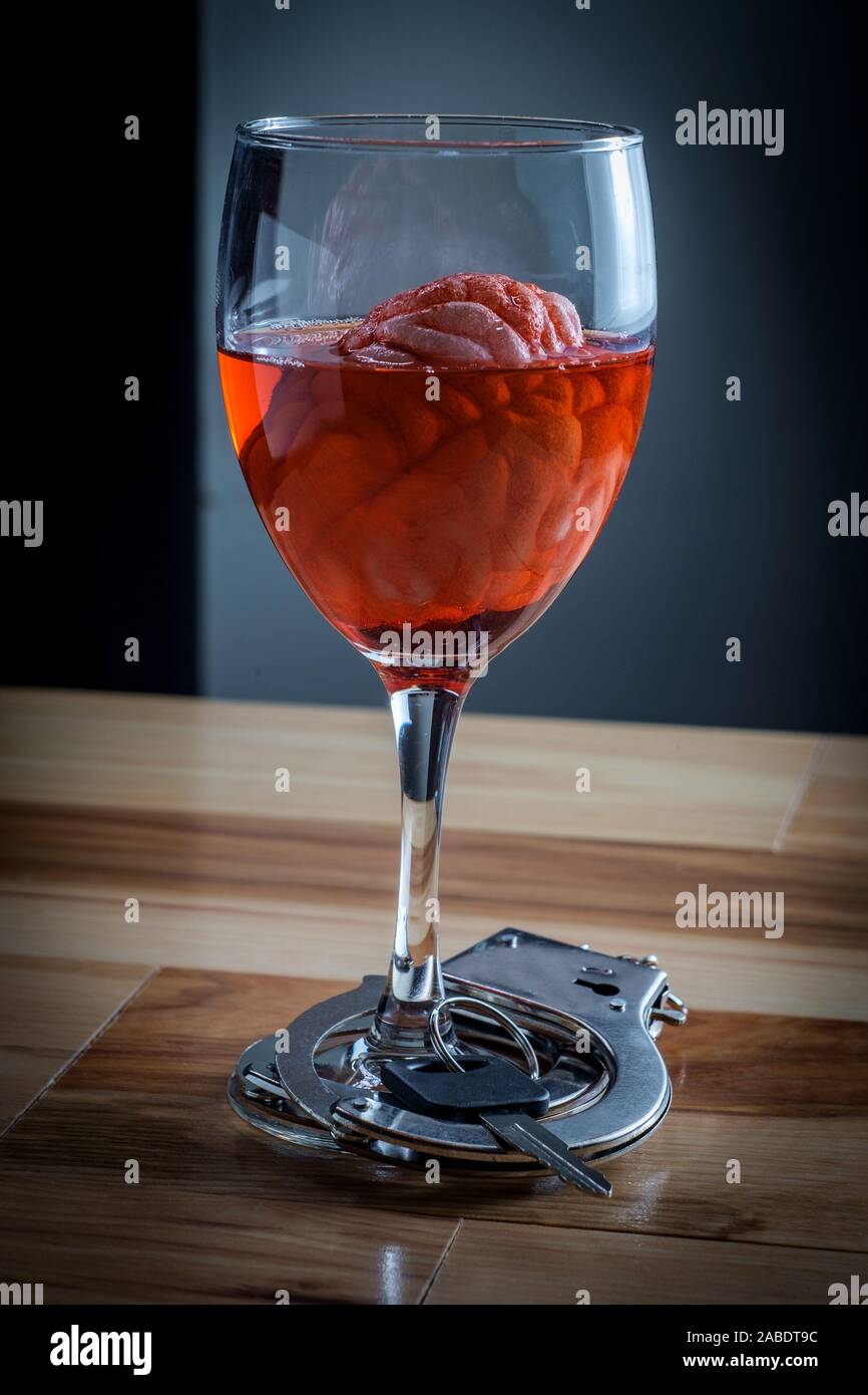 Human brain in red wine glass soaking with car keys and handcuffs for