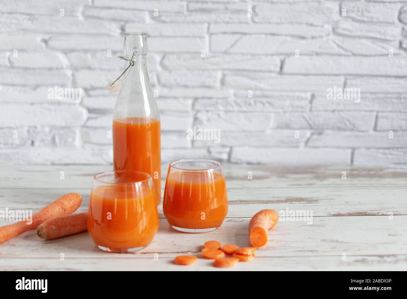Healthy carrot juice in a glass and fresh carrots on a table. Healthy dieting drink in a glass on wooden table background. Stock Photo