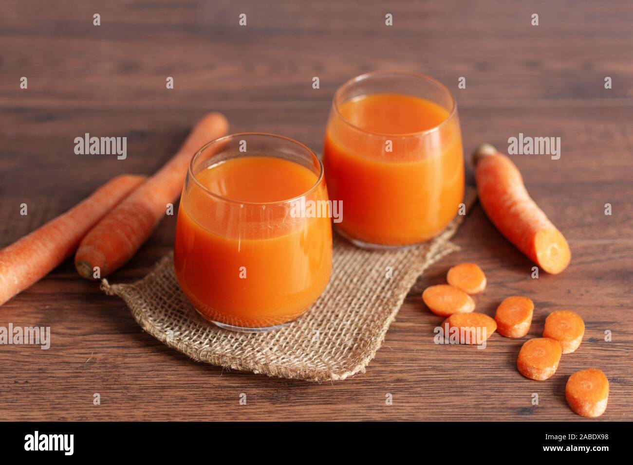 Healthy carrot juice in a glass and fresh carrots on a table. Healthy dieting drink in a glass on wooden table background. Stock Photo