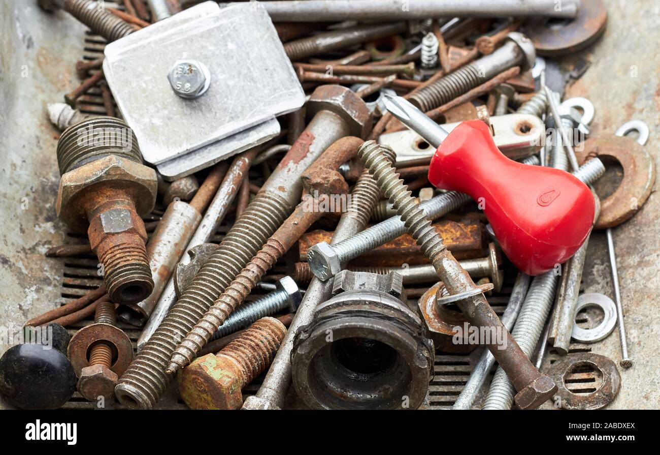 Metallic corroded industrial waste rusty bolts and nuts with red screw