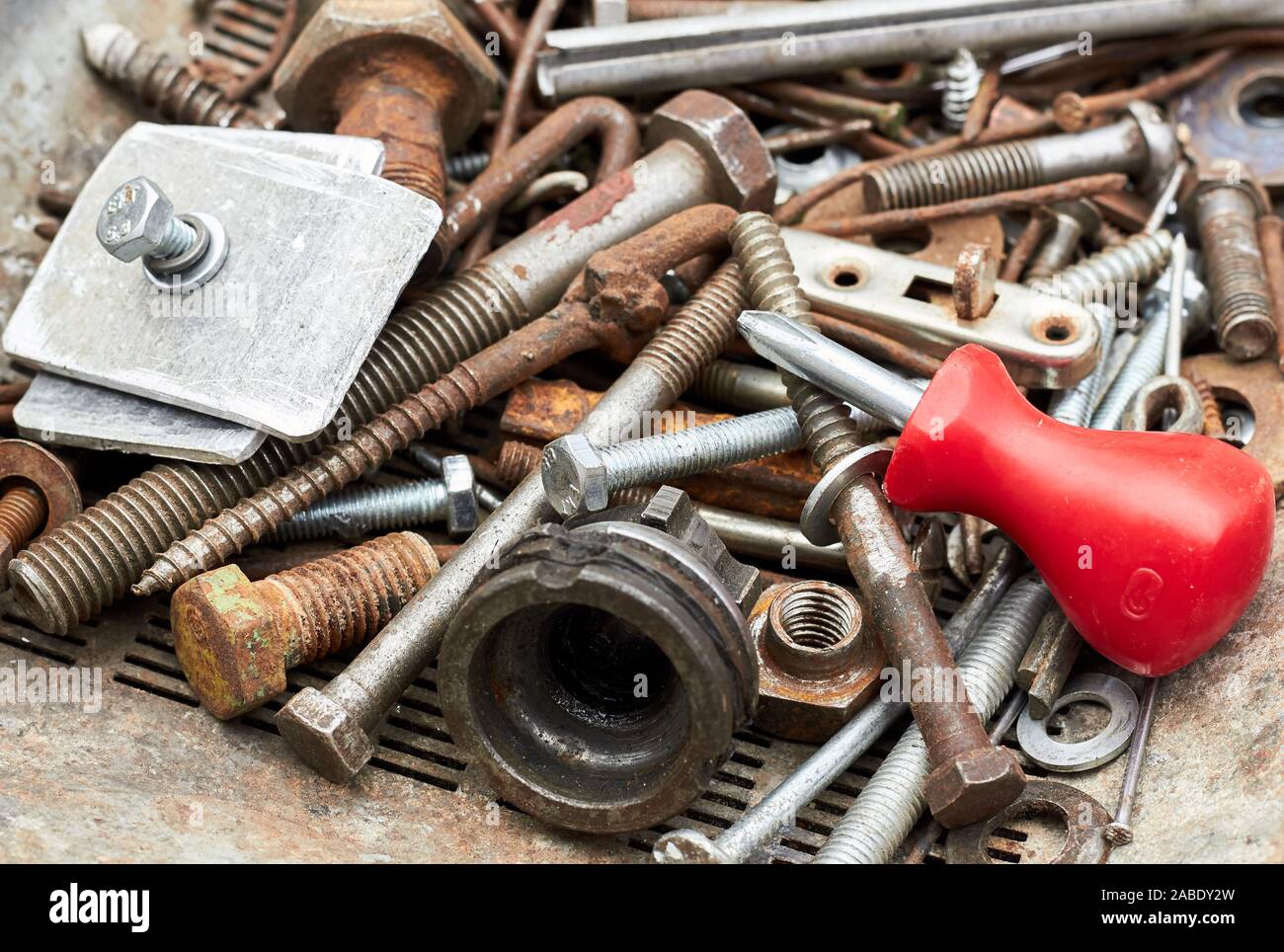 Metallic corroded industrial waste rusty bolts and nuts with red screw