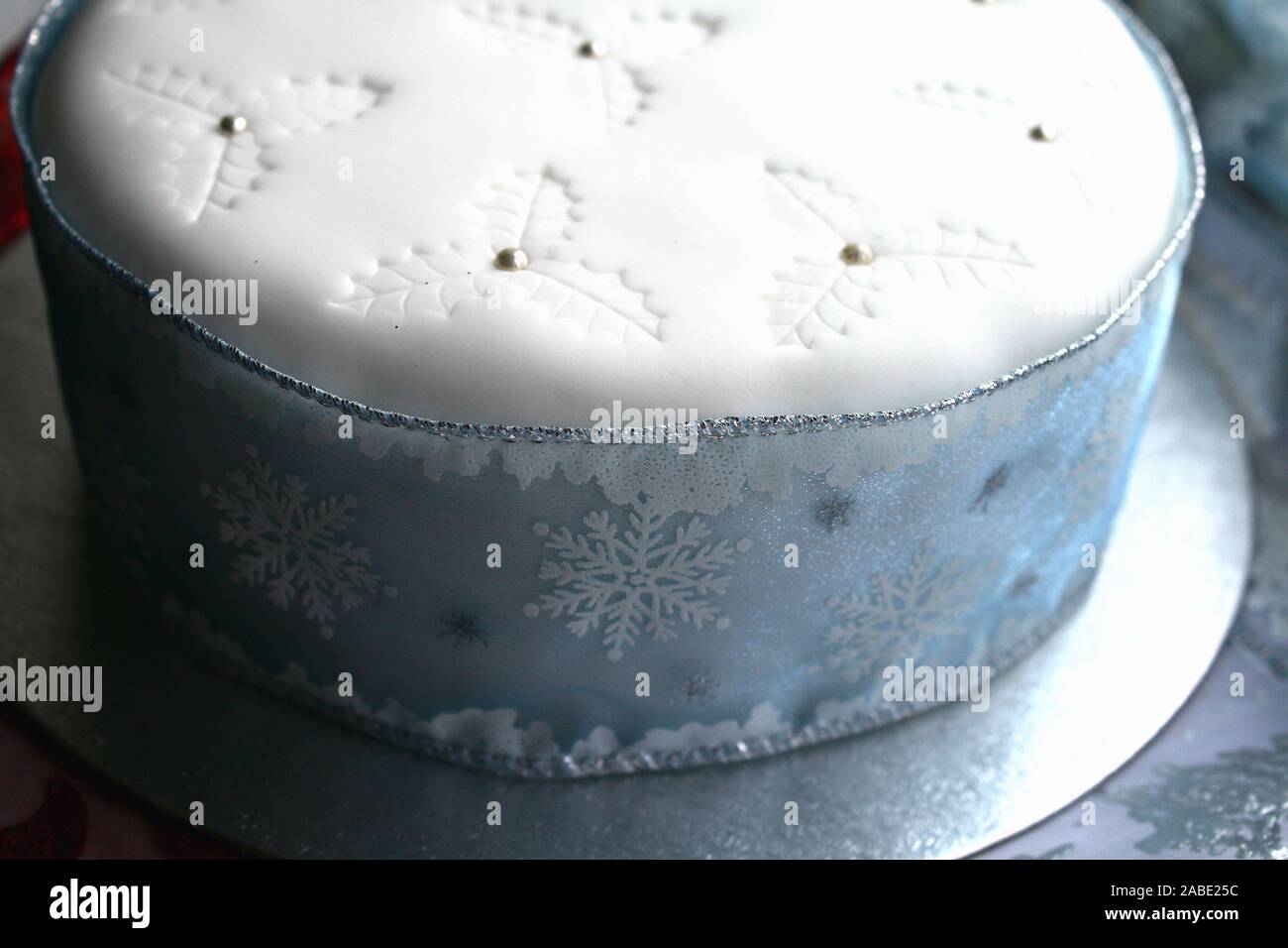 Elegant Blue and white Christmas fruit cake, white icing on top and holy impressions with silver balls, snowflake ribbon all around the cake, blue and Stock Photo