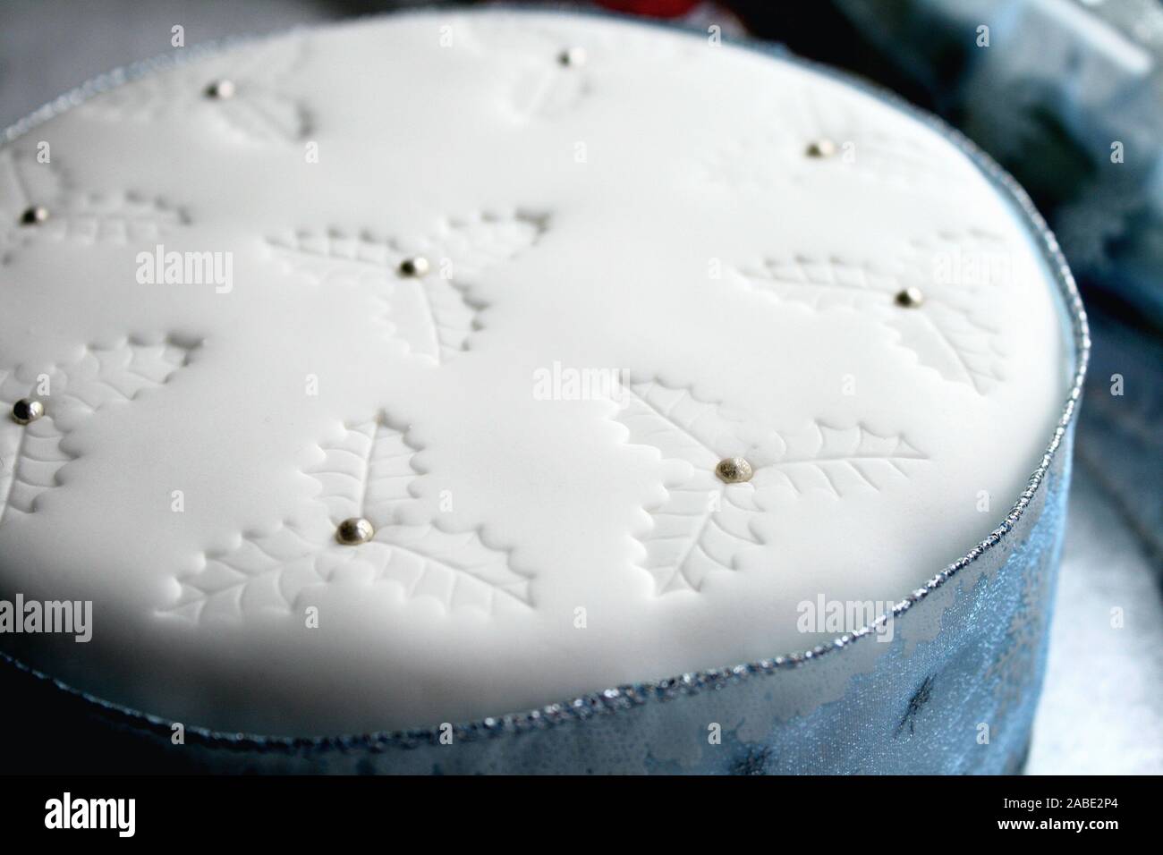 Elegant Blue and white Christmas fruit cake, white icing on top and holy impressions with silver balls, snowflake ribbon all around the cake, blue and Stock Photo