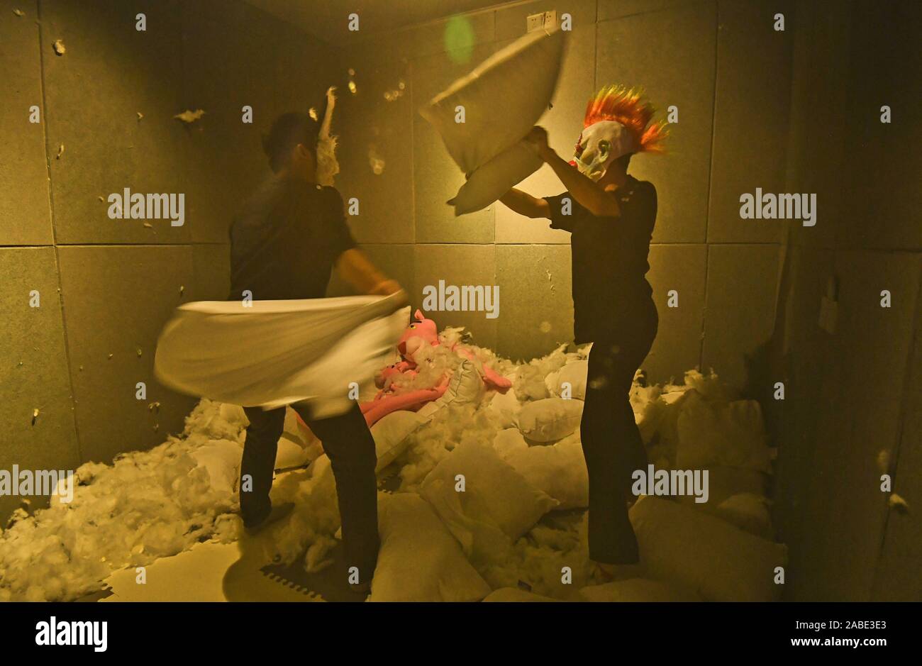 Two visitors fight with pillows to release stress and negative mood at the first frustration venting room opened in Nanning city, south China's Guangx Stock Photo