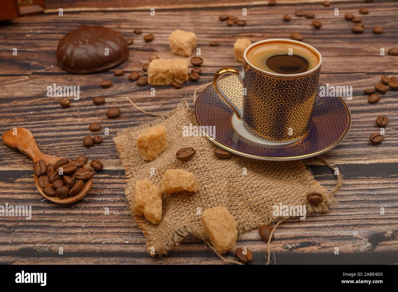 Cup of coffee, brown sugar, coffee beans, marshmallows in chocolate on wooden background Stock Photo