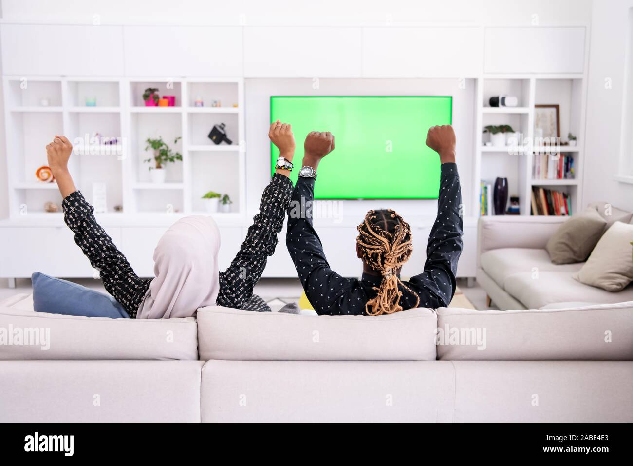 African Couple Sitting On Sofa Watching TV Together Chroma Green Screen  Woman Wearing Islamic Hijab Clothes Stock Photo - Alamy