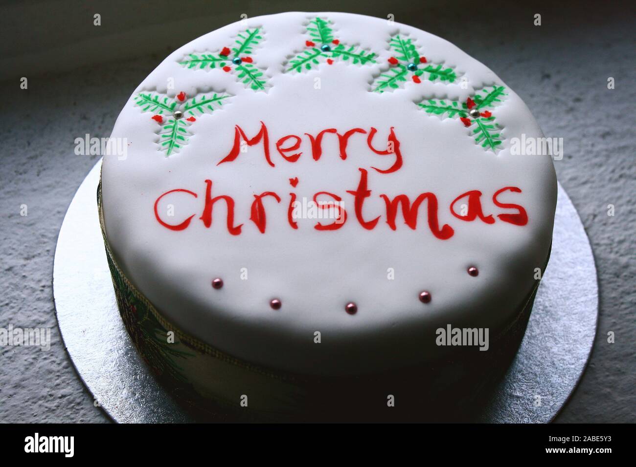 White Christmas cake with painted holy and   Merry Christmas writing on top Stock Photo