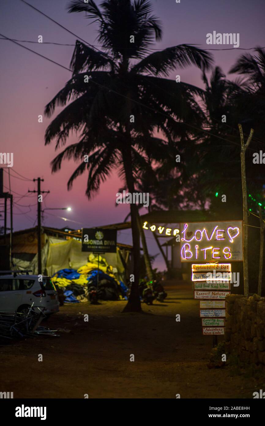 A neon sign leading to a bar in tropical Goa, India,  at sunset. Stock Photo