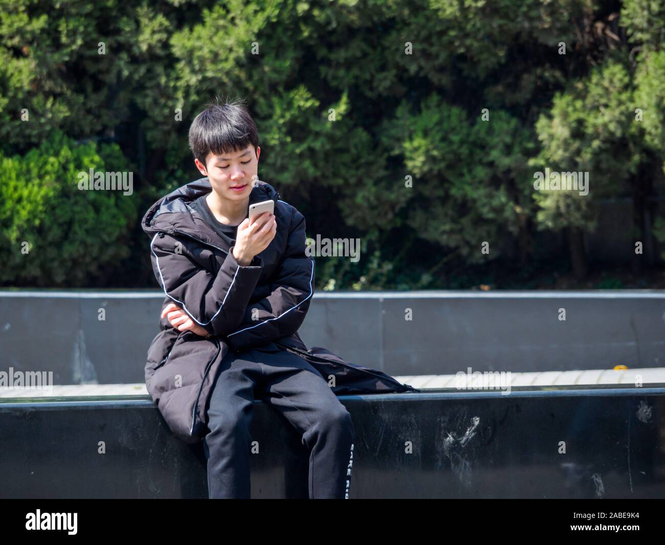 SHANGHAI, CHINA - 12 MAR 2019 - A young Asian Chinese man in casual dress on his vivo smartphone in downtown Shanghai. With copy space. Connected / co Stock Photo