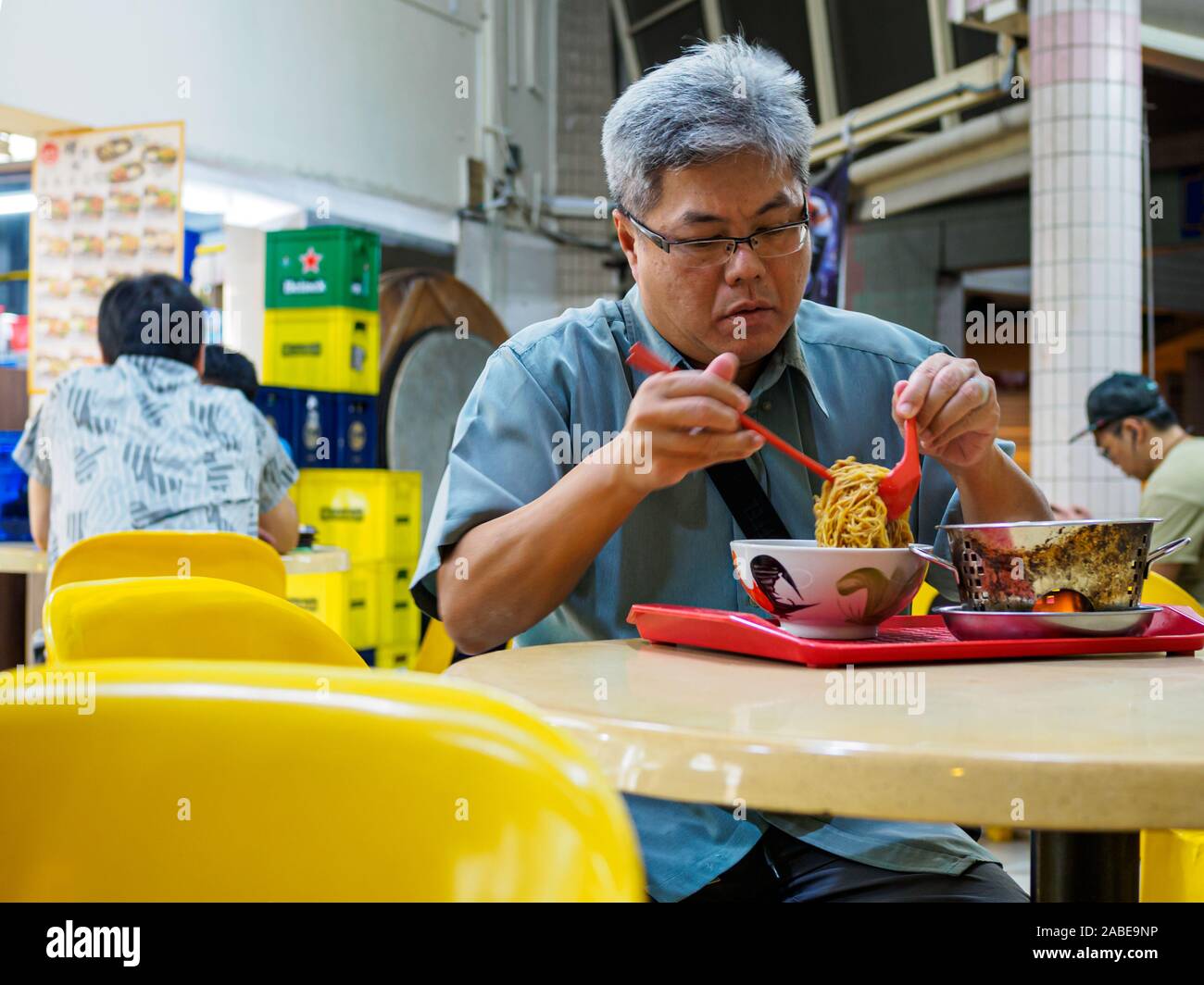 SINGAPORE - 17 MAR 2019 - A middle aged Asian Chinses Singaporean man enjoys a late night bowl of noodles at an eatery / coffeeshop / kopitiam / hawke Stock Photo