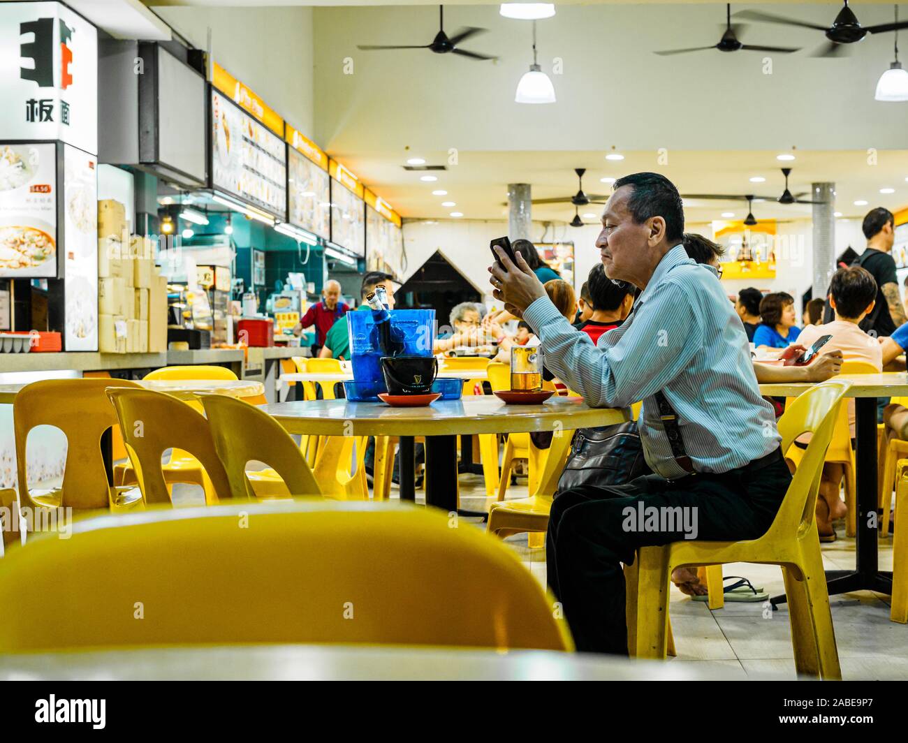 SINGAPORE - 17 MAR 2019 - A middle aged Asian Chinese Singaporean man in office attire enjoys a late night beer at an eatery / coffeeshop / kopitiam, Stock Photo