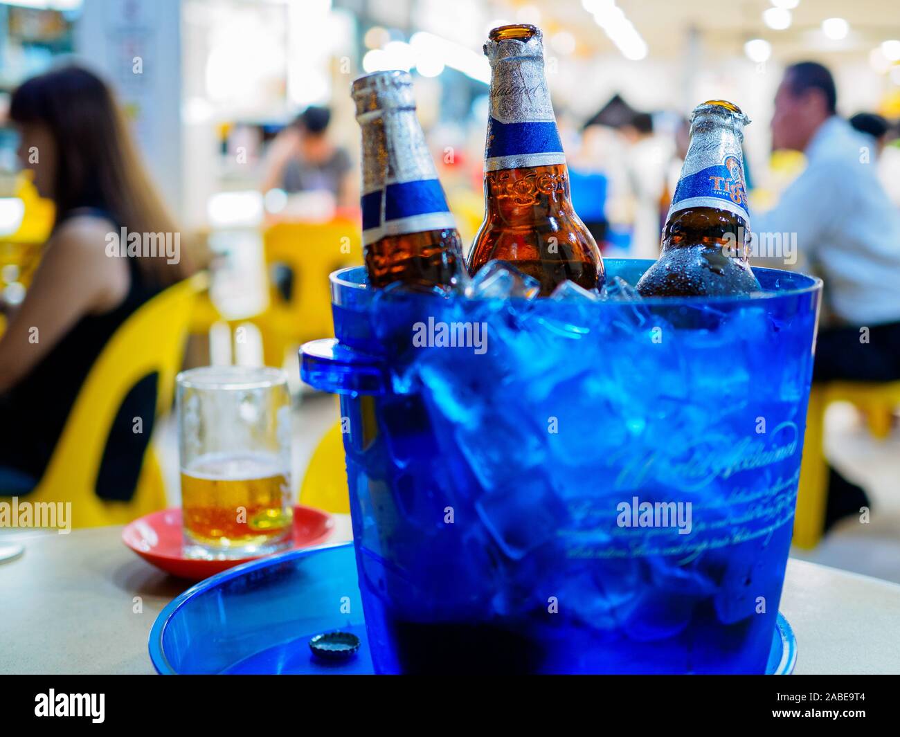 SINGAPORE - 17 MAR 2019 - Bottles of Tiger beer sit in a bucket of ice at a coffeeshop / kopitiam / hawker centre. Drinking beer at a coffeshop is com Stock Photo