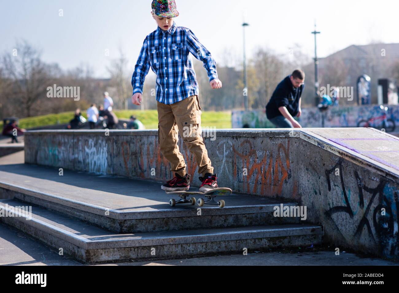 A cute little boy with ADHD, Autism, Asperger syndrome burns off energy at the Skateboard park, practicing tricks such as the ollie and jumping steps Stock Photo