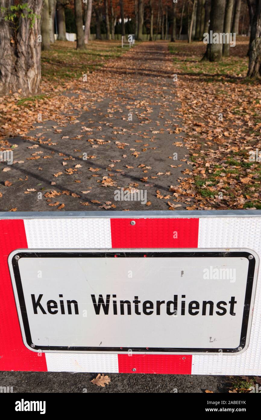 A red and white sign on a footpath at the entrance of a park in Nuremberg informs Kein Winterdienst  (in English: no winter service ). Seen in Francon Stock Photo