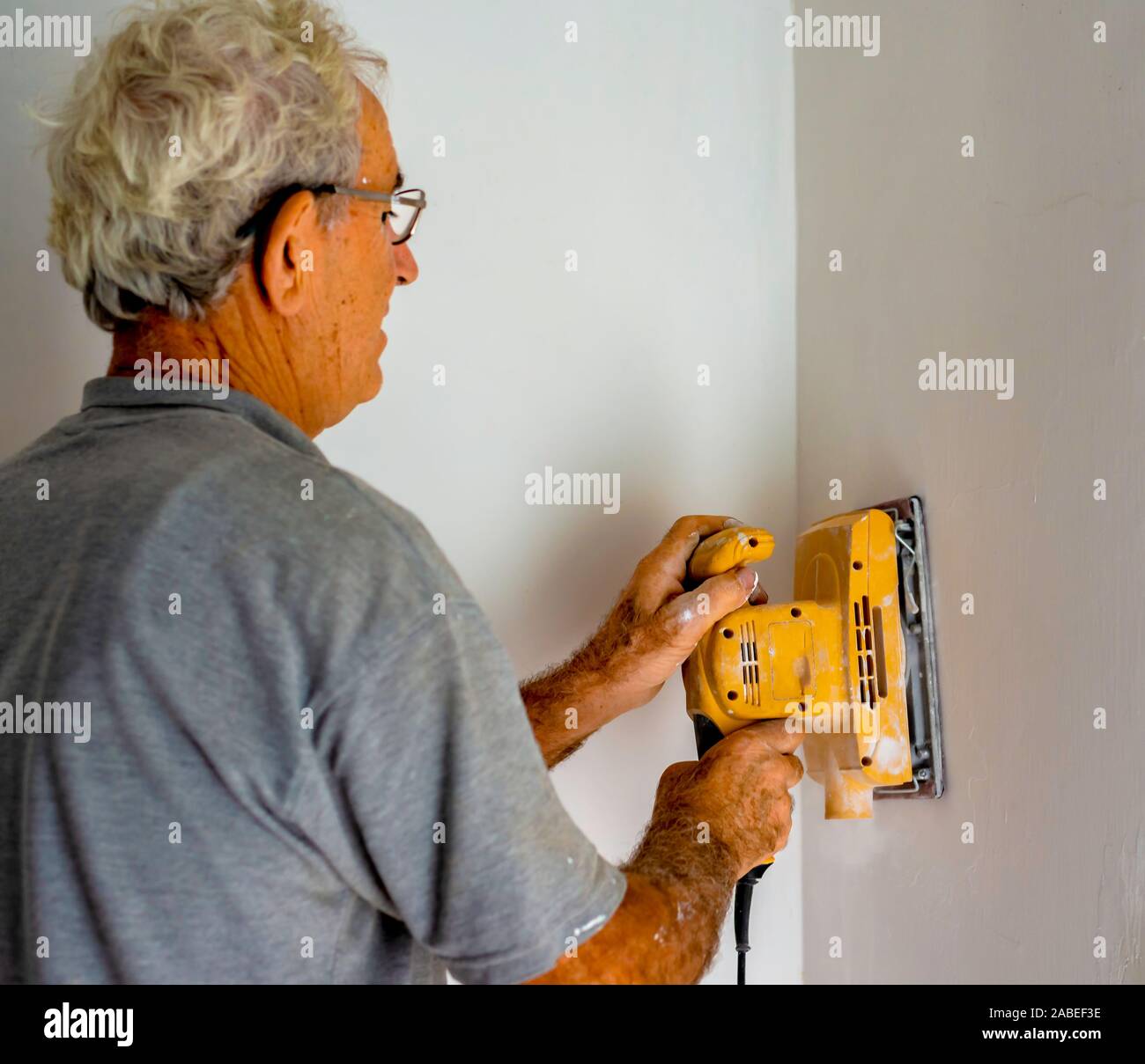 Worker with an orbital sander smoothes a wall Stock Photo - Alamy