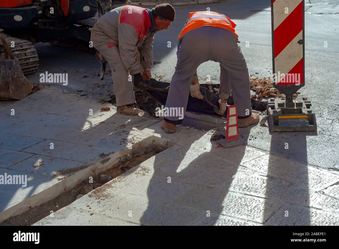 Execution of fiber optic distribution network for telecommunications. Workers position the cast iron manhole covers on manholes Stock Photo