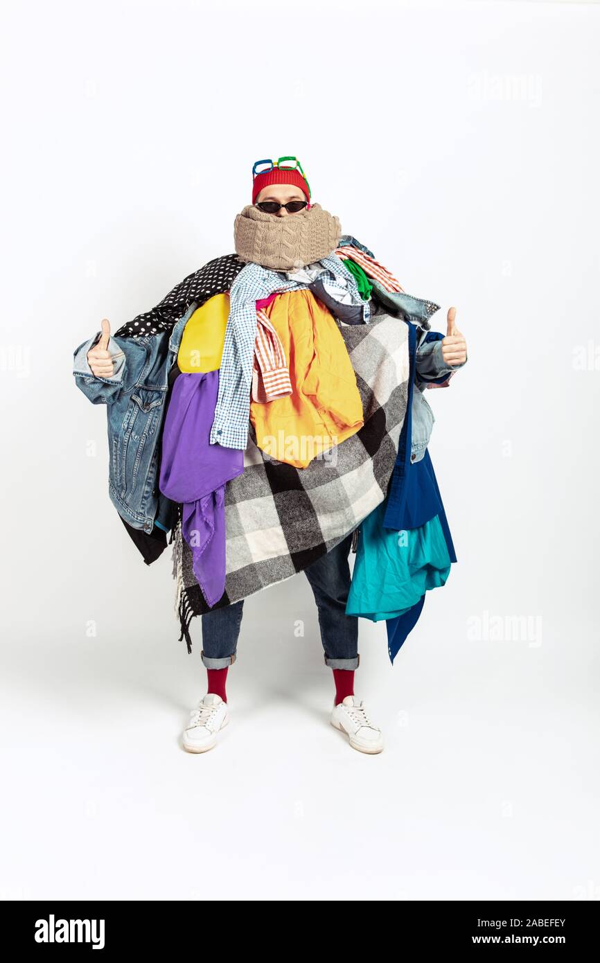 Man addicted of sales, clothes, overproduction and crazy demand. Female  model wearing too much colorful clothes, need more things to be happy.  Fashion, style, black friday, sale, abusing purchases Stock Photo -