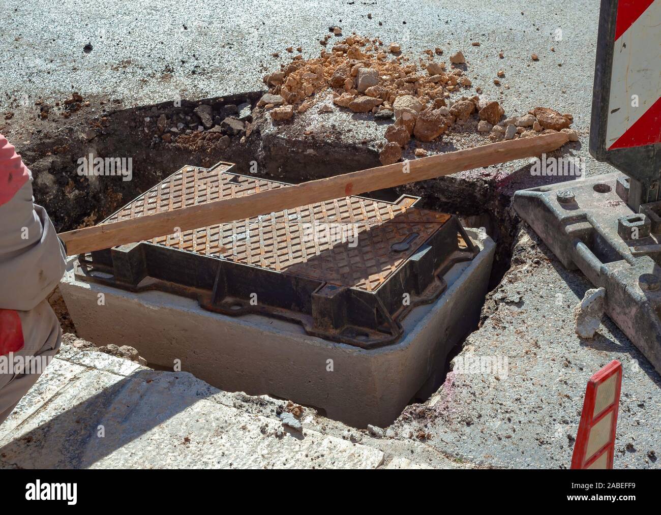 Execution of fiber optic distribution network for telecommunications. Workers position the cast iron manhole covers on manholes Stock Photo