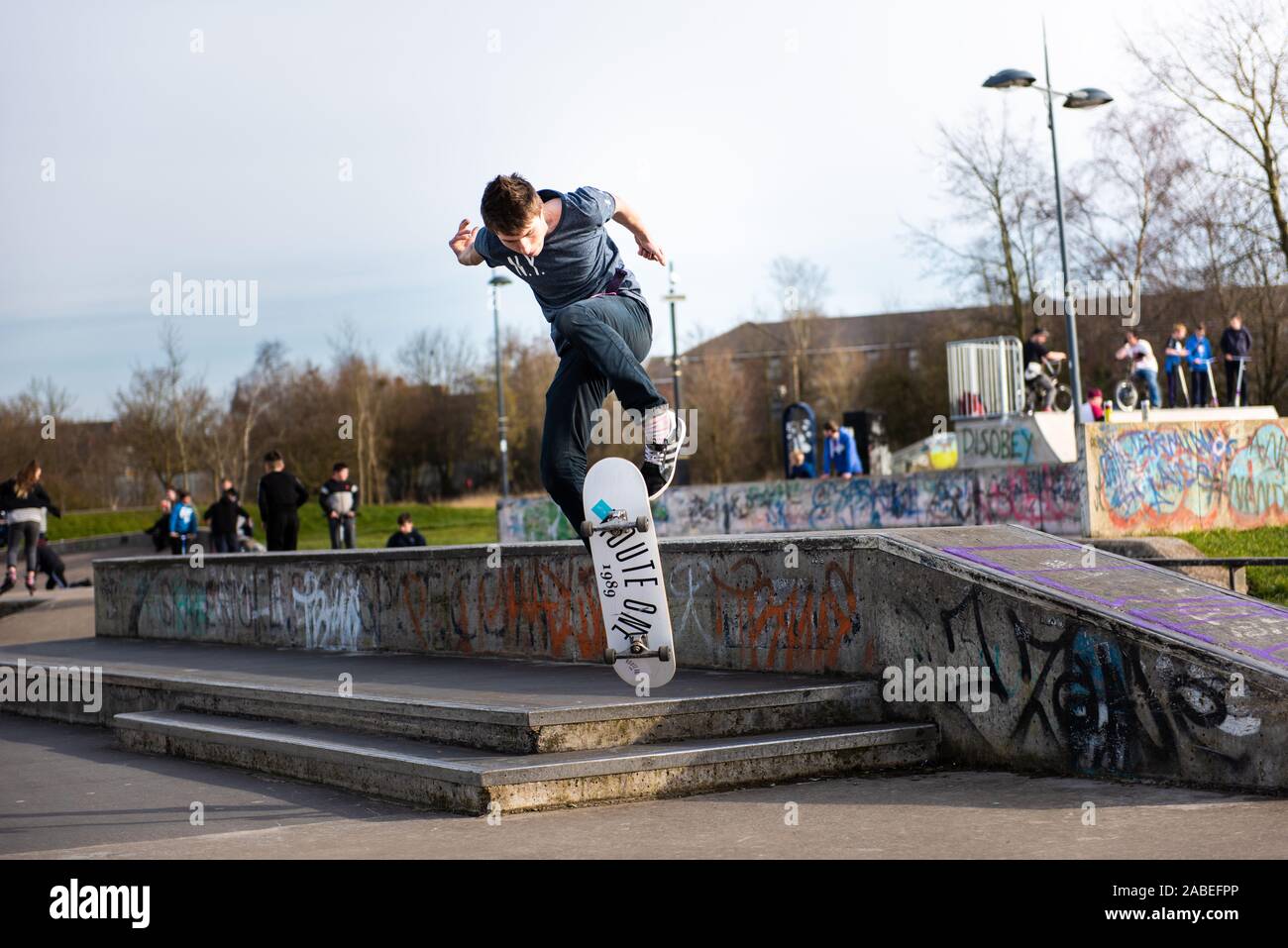 Young guys practice ollie's and tricks at the concrete skate park in