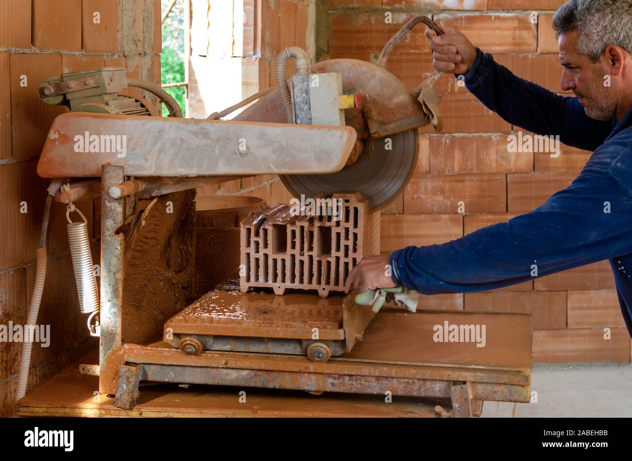 Worker using an angle grinder or circular saw cutting bricks in construction site Stock Photo