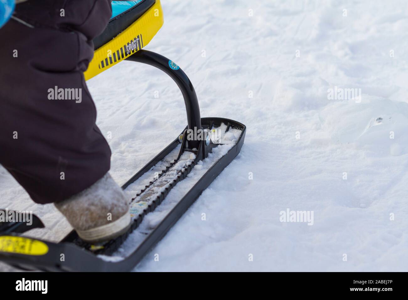Little boy sitting on snow scooter. Close up. Winter health lifestyle concept. Stock Photo