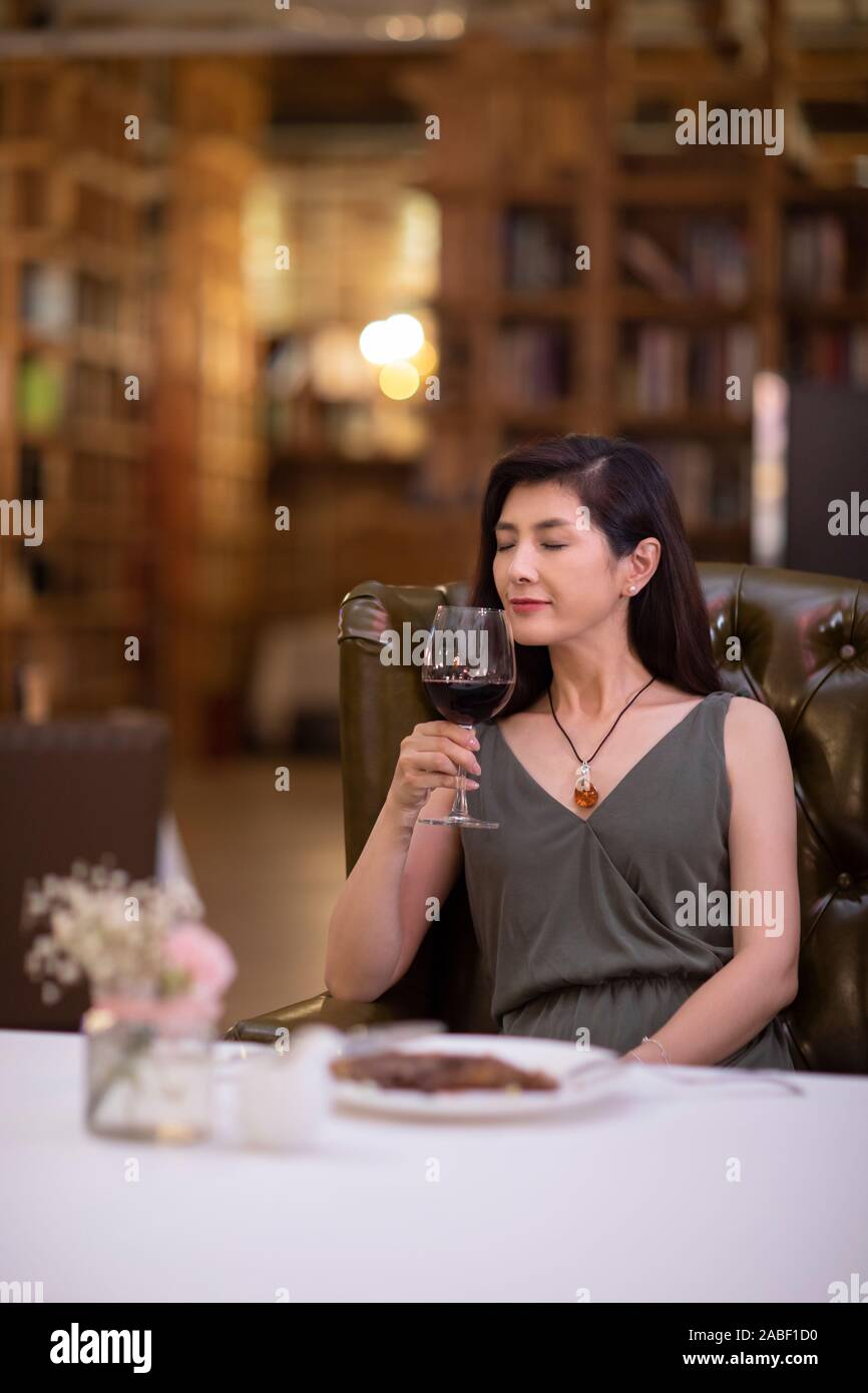 Elegant woman enjoying red wine in western restaurant Stock Photo - Alamy