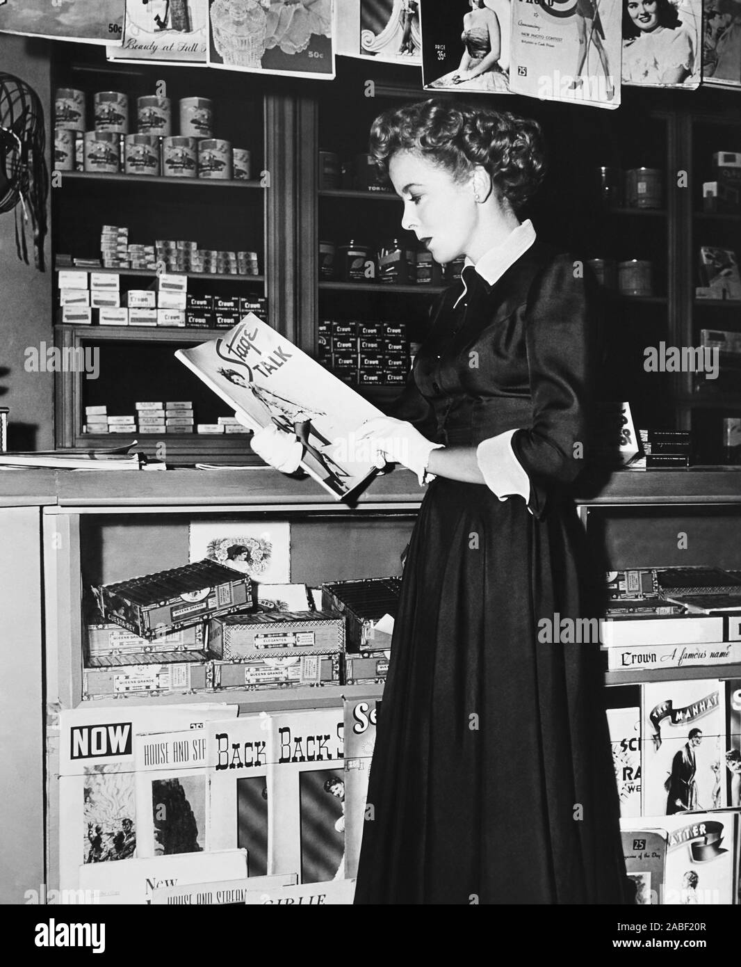 Prop Magazine WOMAN IN HIDING, Ida Lupino examining the prop magazines at the cigar ...