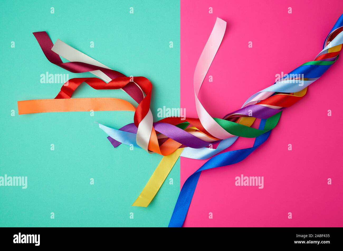 many silk multi-colored ribbons on a colored background, top view Stock Photo