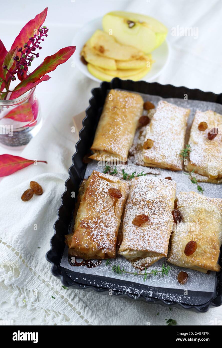 Top view of homemade phyllo dough rolls with apples and orange marmalade. White background with sultanas. Stock Photo